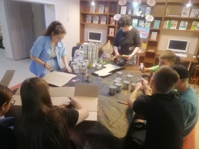 участники мастер-класса за столом приготовили материалы для изготовления свечей: консервные банки, картон, 