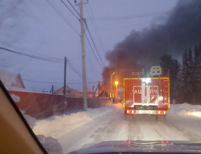 Вид из автомобиля на пожарный автомобиль, стоящий впереди, и на горящий дом 