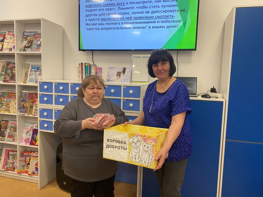 Участница мероприятия складывает в &laquo;Коробку доброты&raquo; корм для кошек из приюта. Коробку держит Мойсюк О.В.