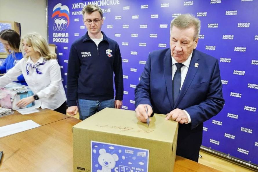 Председатель Думы Югры Борис Хохряков подписывает коробки с подарочными наборами