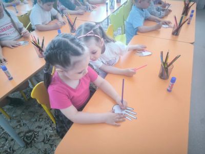 ребята за столами раскрашивают бумажные ладошки