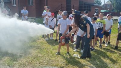 сотрудник МЧС показывает мальчику как использовать онетушитель