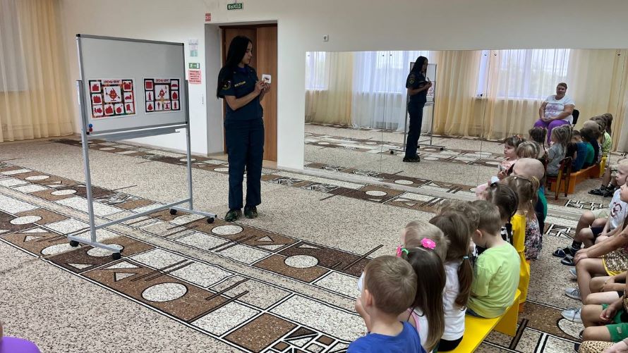 сотрудник пожарной безопасности показывает детям карточки
