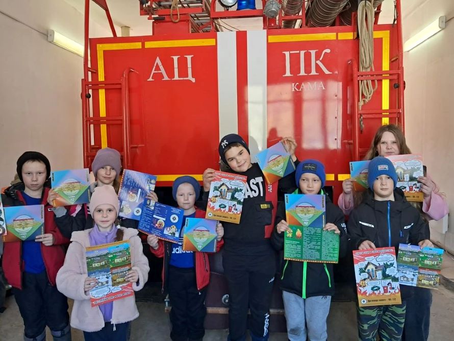 Фото детей на фоне пожарной машины с памятками по противопожарной безопасности в руках