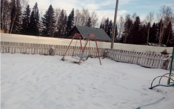 фотография заброшенной и занесенной снегом небольшой детской площадки